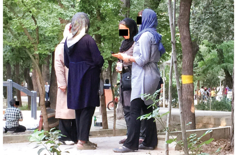 Iranian Front Line Workers Always Prepared to be Imprisoned a group of women stand together outside talking with black boxes over their eyes